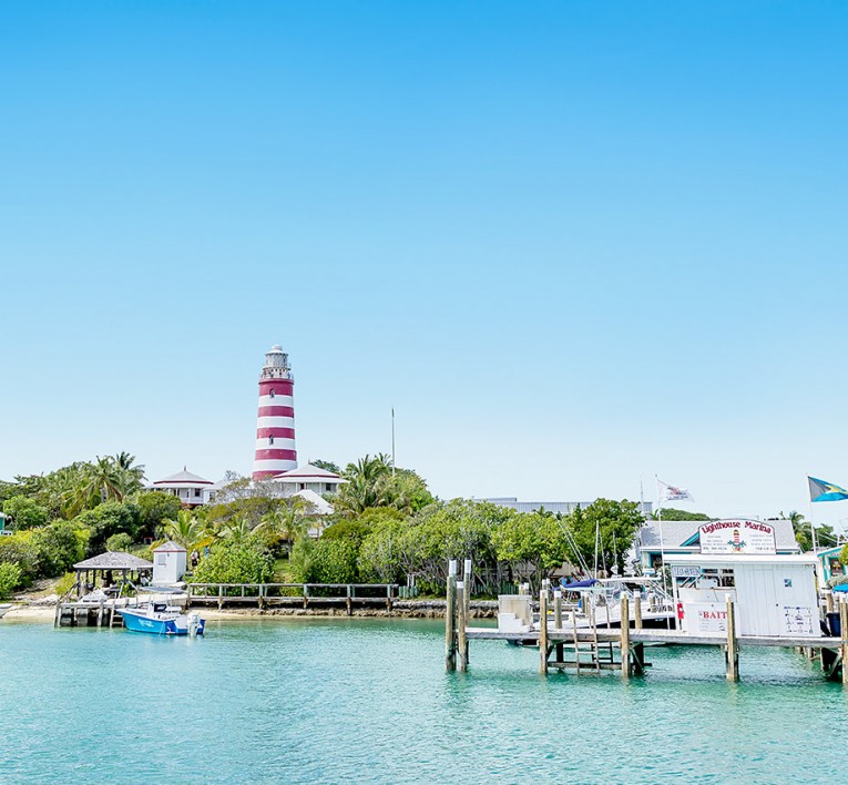 red and white striped light house with view of marina at the forefront 