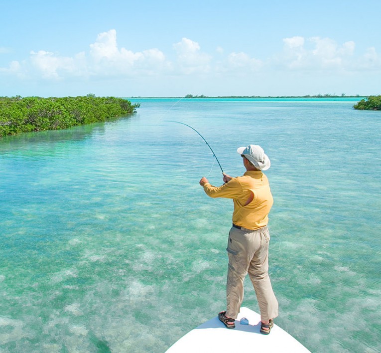 man on the bow of a small boat holding a fishing rod