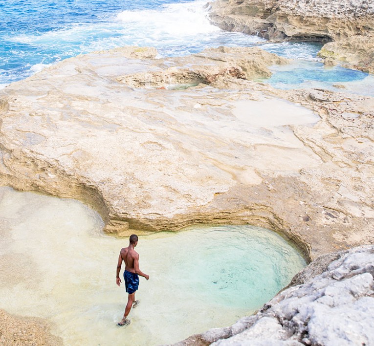 Man walking in Queen's Bath rocks in Eleuthera Bahamas 