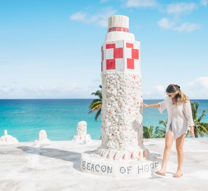 a person standing next to a tall tower on a beach