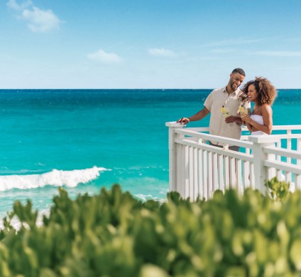 a man and woman standing on a white railing overlooking the ocean