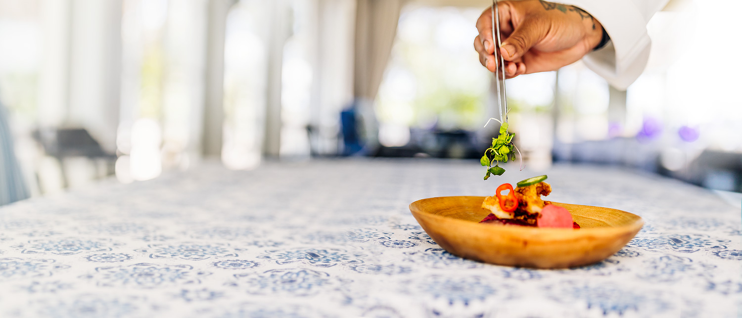 a picture of someone adding garnish to a dish 