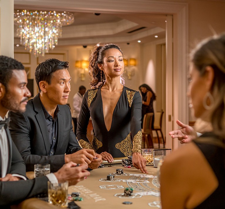 People standing at poker table with cards and chips 