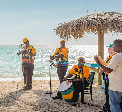 a group of men playing drums on a beach 424x389px