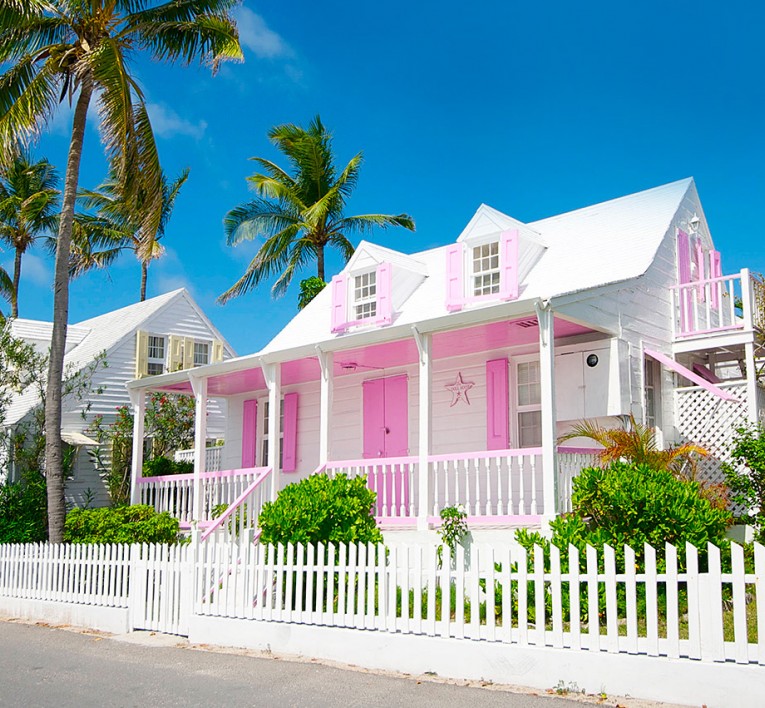 bright prink house with white trimmings and white picket fence