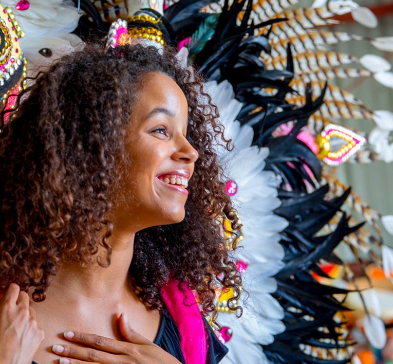 a woman with colorful feathered bahamian costume piece on her back